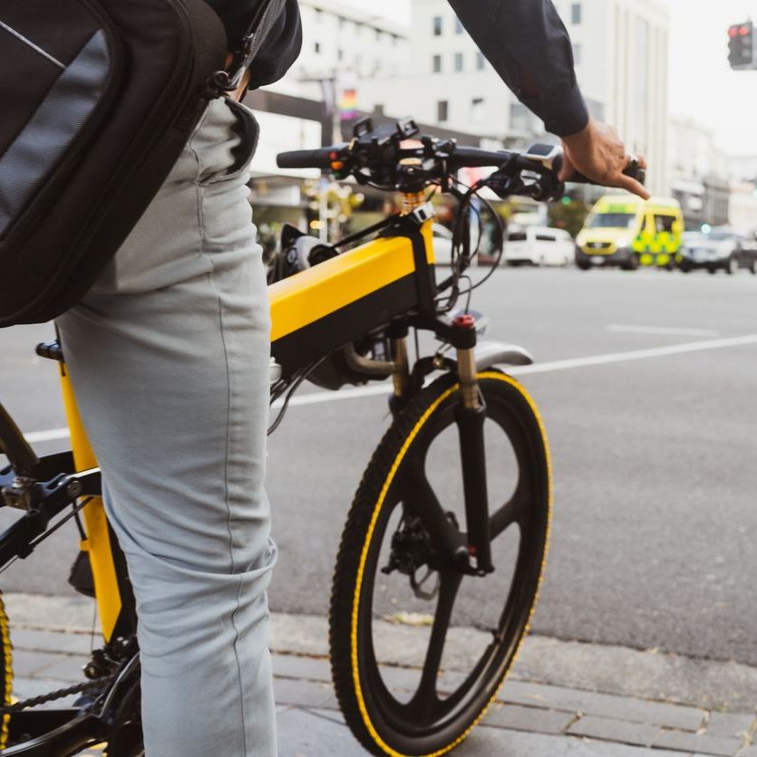 The portrait of a businessman using electric bicycle to go to work in cityscape.